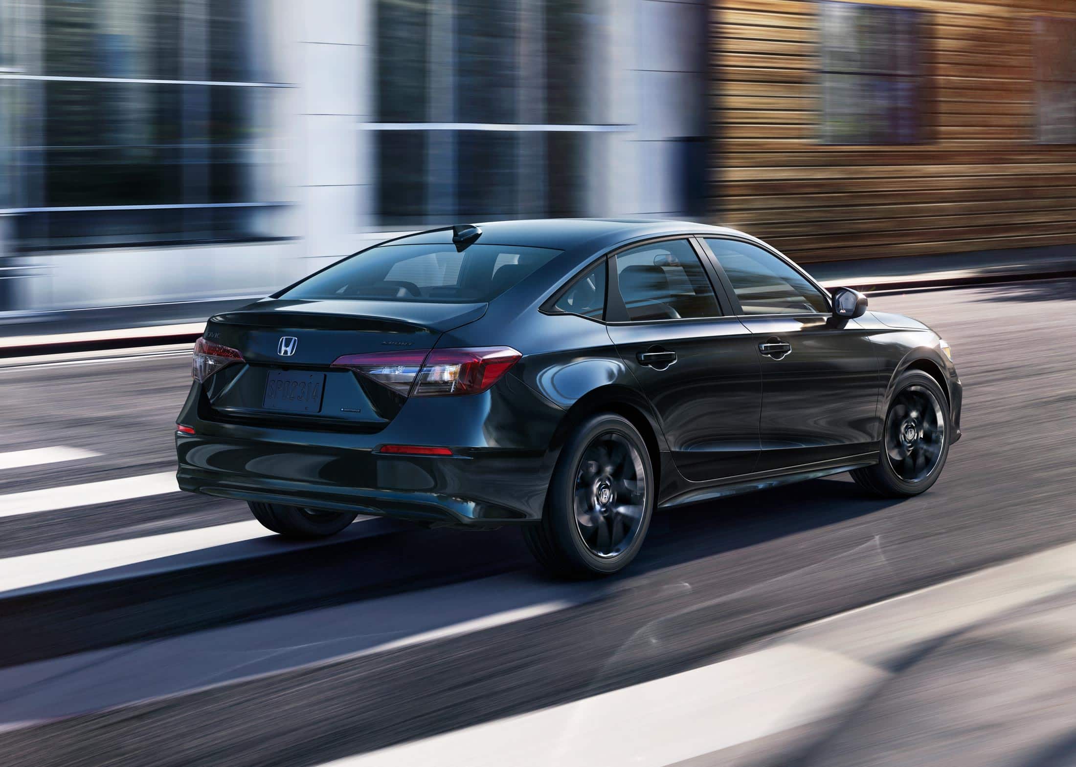 2026 Honda Civic Sedan Sport Hybrid in Crystal Black Pearl rear three-quarter view driving on a city street (Compact Sedan)